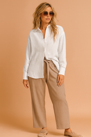 Witte damesblouse met luchtige structuurstof, knoopsluiting, lange mouwen en casual rechte zoom, losvallend silhouet.