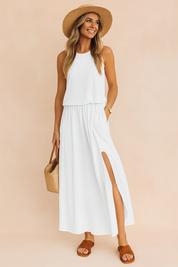 Witte mouwloze maxi-jurk van soepele stof met hoge split en ronde hals, ideaal voor strand- en zomerdagen.