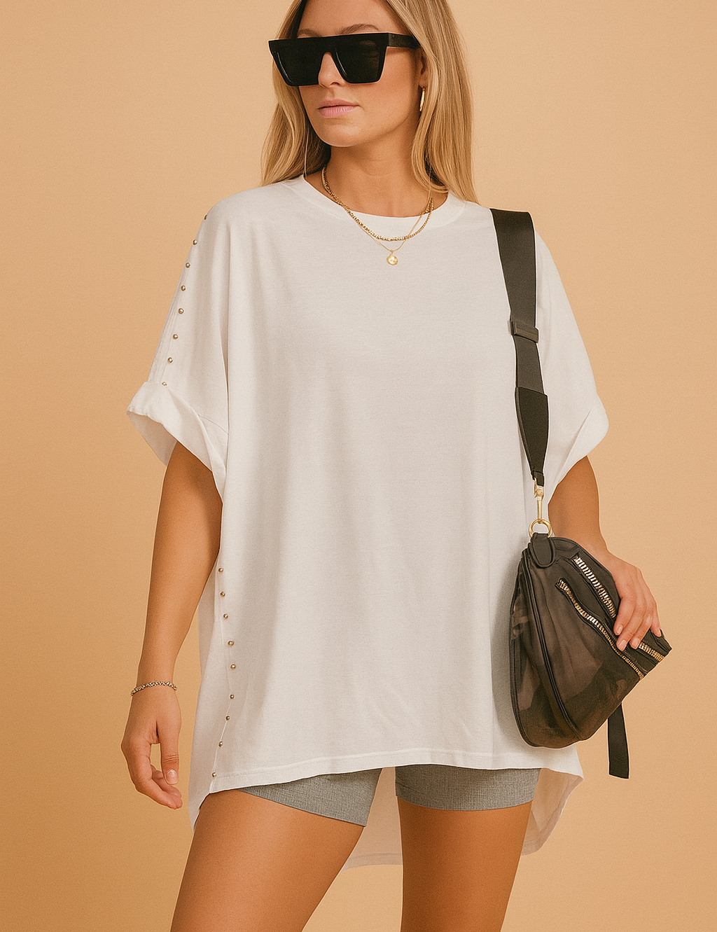 Witte oversized tuniek met ronde hals en decoratieve zilveren studs langs de zijkanten en mouwen.