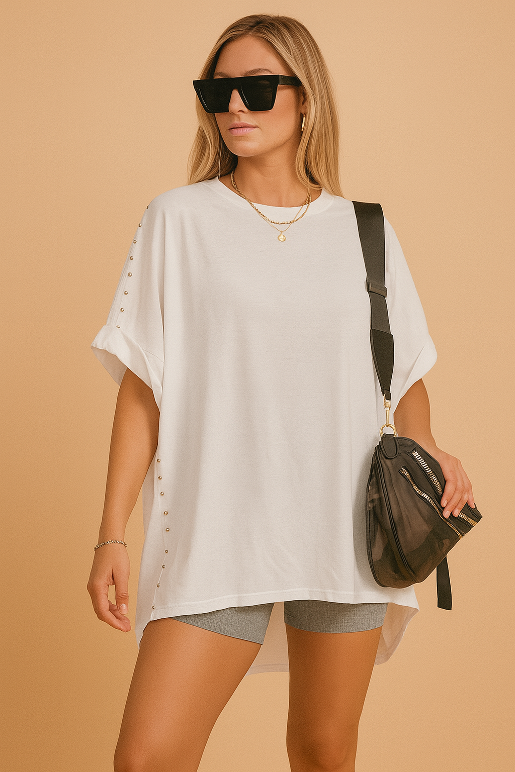 Witte oversized tuniek met ronde hals en decoratieve zilveren studs langs de zijkanten en mouwen.