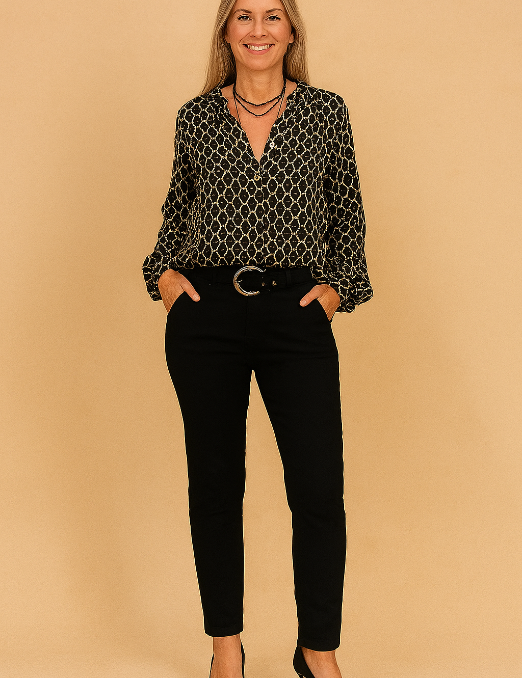 Zwarte blouse met lange mouwen, V-hals en beige kettingpatroon, uitgevoerd in luchtige stof met licht glanzende afwerking.
