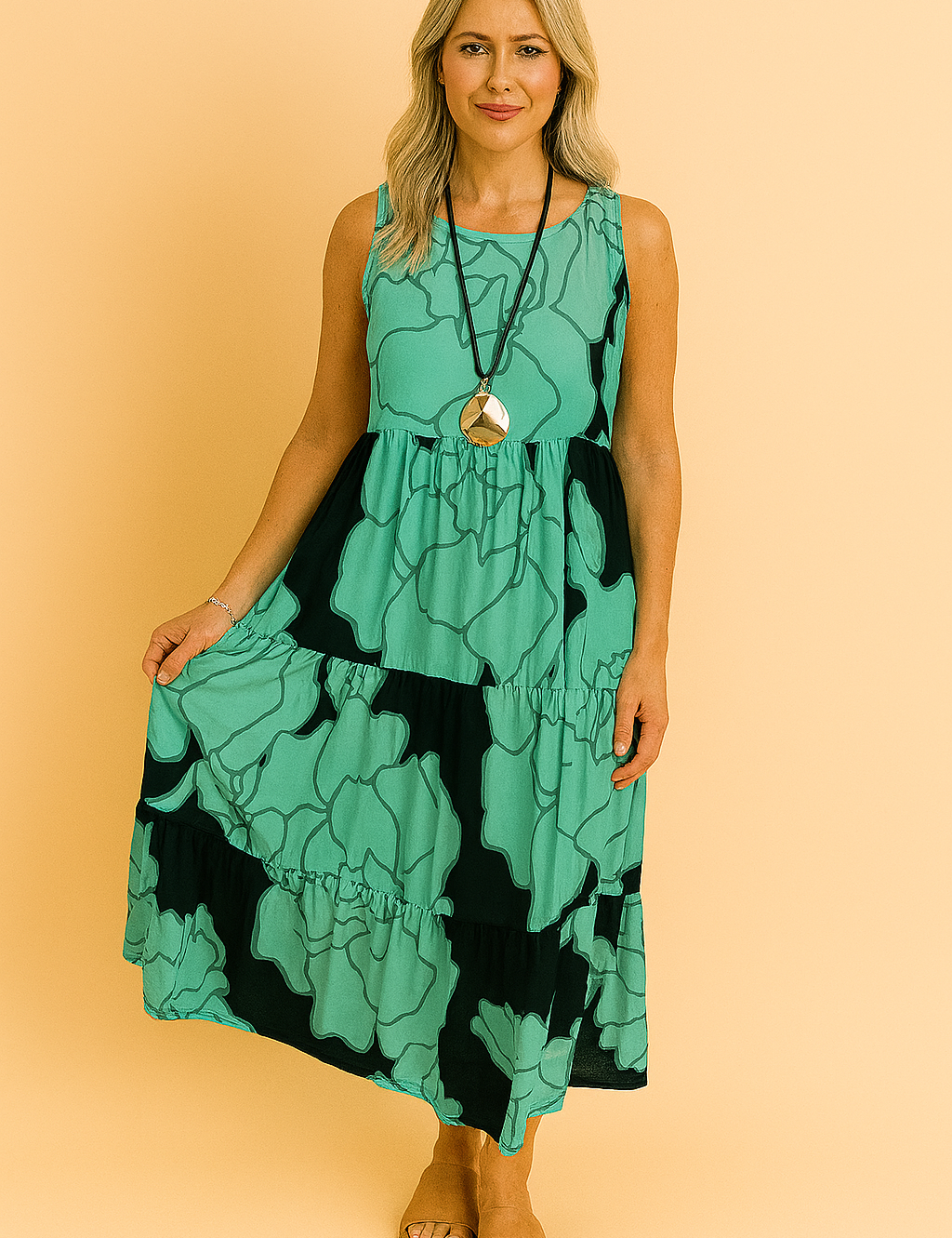 Mouwloze midi-jurk in aqua groen met zwarte oversized bloemenprint en gelaagde ruches voor een luchtige zomerse uitstraling.