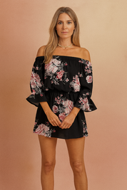 Off-shoulder playsuit met roze bloemenprint op zwarte achtergrond, elastische taille en uitlopende mouwen