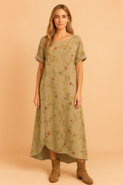 Olijfgroene linnen jurk met fijne geborduurde bloemen in zachte kleuren en asymmetrische knoopsluiting.