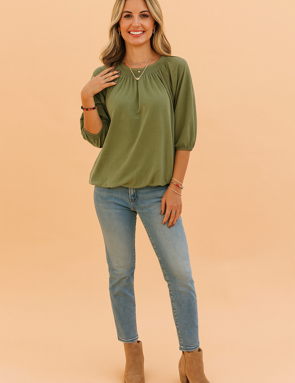 Olijfgroene dames top met ronde hals en driekwartmouwen, uitgevoerd in een zachte jersey stof. Voorzien van elegante plooien rond de halslijn en elastische mouwboorden voor een subtiele pofmouw. De losvallende pasvorm biedt zowel comfort als een vrouwelijke uitstraling.