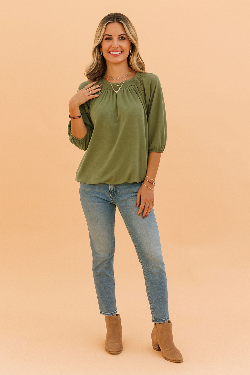 Olijfgroene dames top met ronde hals en driekwartmouwen, uitgevoerd in een zachte jersey stof. Voorzien van elegante plooien rond de halslijn en elastische mouwboorden voor een subtiele pofmouw. De losvallende pasvorm biedt zowel comfort als een vrouwelijke uitstraling.