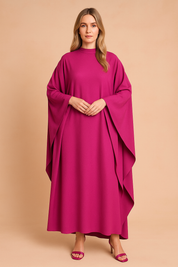 Fuchsia roze maxi jurk met losvallende vleermuismouwen en hoge halslijn, opvallend en stijlvol.