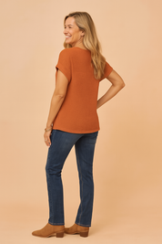 Roestkleurig dames T-shirt met wafelstructuur en korte opgerolde mouwen, achteraan langer vallend voor extra bedekking en comfort. Casual top met een rechte pasvorm.