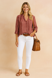 Vrouwelijk model draagt een rood-wit gestreeerde linnen blouse met knoopsluiting en opgerolde mouwen, gecombineerd met een witte skinny jeans.