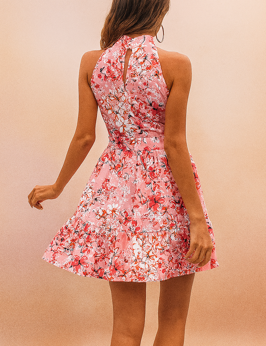 Vrouw draagt roze bloemen halternek mouwloze mini jurk met taille strik