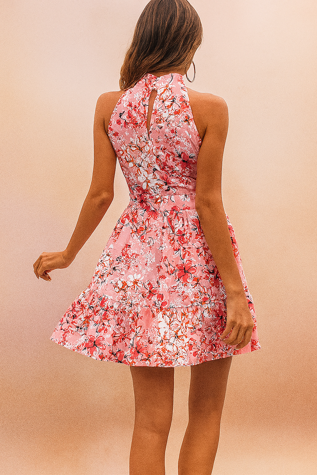 Vrouw draagt roze bloemen halternek mouwloze mini jurk met taille strik