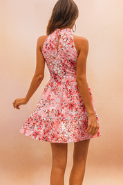Vrouw draagt roze bloemen halternek mouwloze mini jurk met taille strik