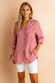 Lichtroze blouse in kreukstof met lange mouwen en knoopsluiting, gestyled met witte short.