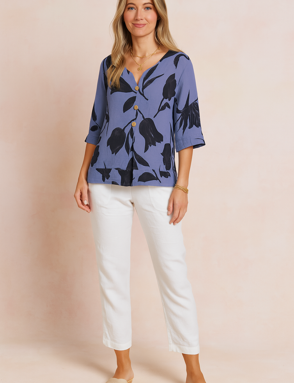 Blouse in stoffige blauwe tint met zwarte tulpenprint, korte zoom, driekwartmouwen en knoopsluiting aan de voorkant voor een moderne en luchtige uitstraling.