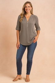 Stijlvolle taupekleurige damesblouse met een gladde, effen stof, voorzien van een halve rits aan de voorkant en opgerolde 3/4-mouwen met knoopdetail. Ideaal voor een casual of zakelijke look.