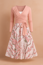 Mouwloze roze midi-jurk met spaghettibandjes en een bloesemprint in roze en groen over de hele stof, ontworpen met een flatterende A-lijn snit.