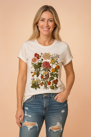 Gebroken wit T-shirt van katoen met kleurrijke botanische bloemenprint op de voorkant, waaronder realistische rode, roze, gele en oranje veldbloemen met fijne stelen en bladstructuur.
