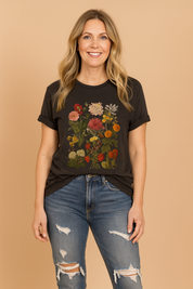 Zwarte T-shirt van jersey met opvallende botanische print in warme tinten, met een gedetailleerd patroon van verschillende veldbloemen en bladeren op de borst.