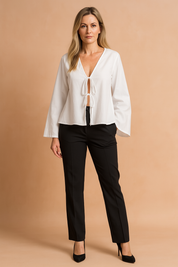 Witte blouse met diepe V-hals, dubbele striksluiting aan de voorkant en wijd uitlopende mouwen in luchtige stof.