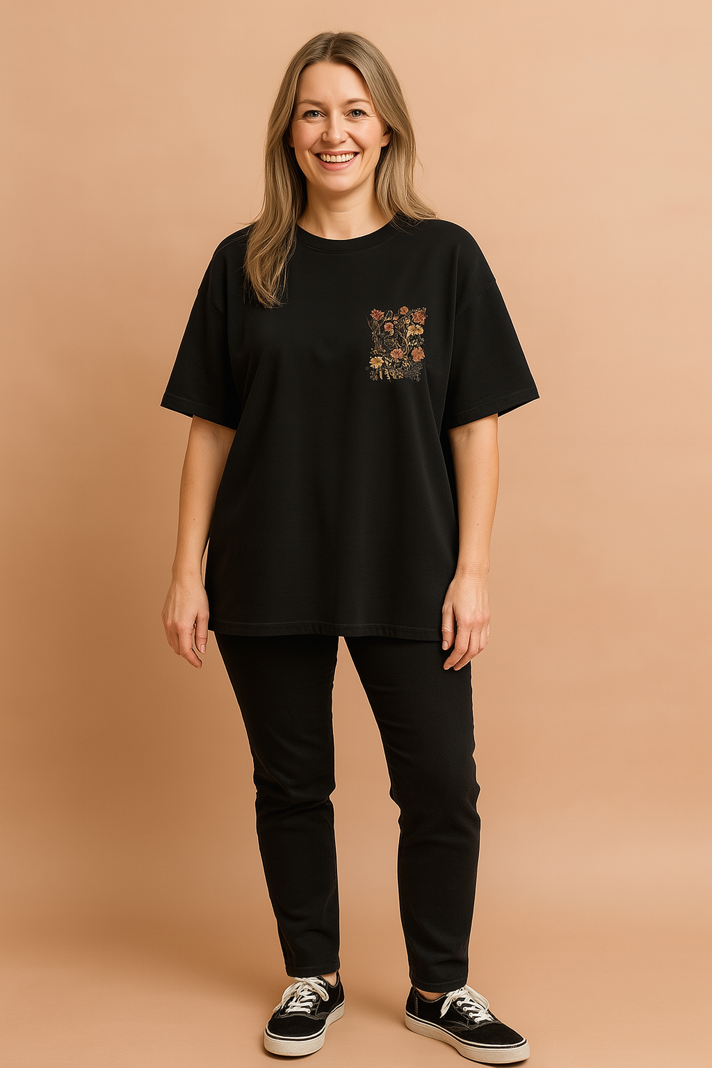 Zwart dames T-shirt met ronde hals en korte mouwen, uitgevoerd in een losse pasvorm. Op de linkerborst bevindt zich een decoratief bloemenmotief in geborduurde stijl, met warme herfsttinten die contrasteren tegen de effen achtergrond. Gemaakt van zachte katoenen jersey, perfect voor casual dagelijks gebruik.