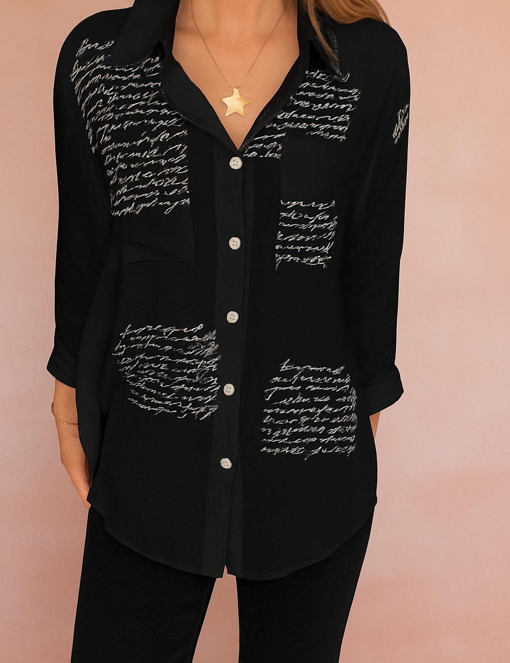 Alt-tekst (NL): Zwarte blouse met handgeschreven witte tekstprint en knoopsluiting aan de voorkant, gemaakt van luchtige stof.