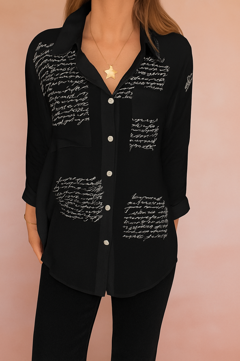Alt-tekst (NL): Zwarte blouse met handgeschreven witte tekstprint en knoopsluiting aan de voorkant, gemaakt van luchtige stof.