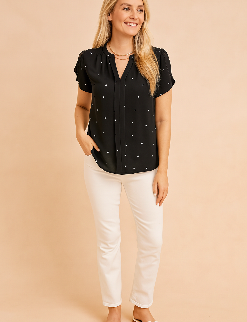 Zwarte blouse met korte mouwen en witte hartjesprint, met keyhole-halslijn en lichte, elegante afwerking.