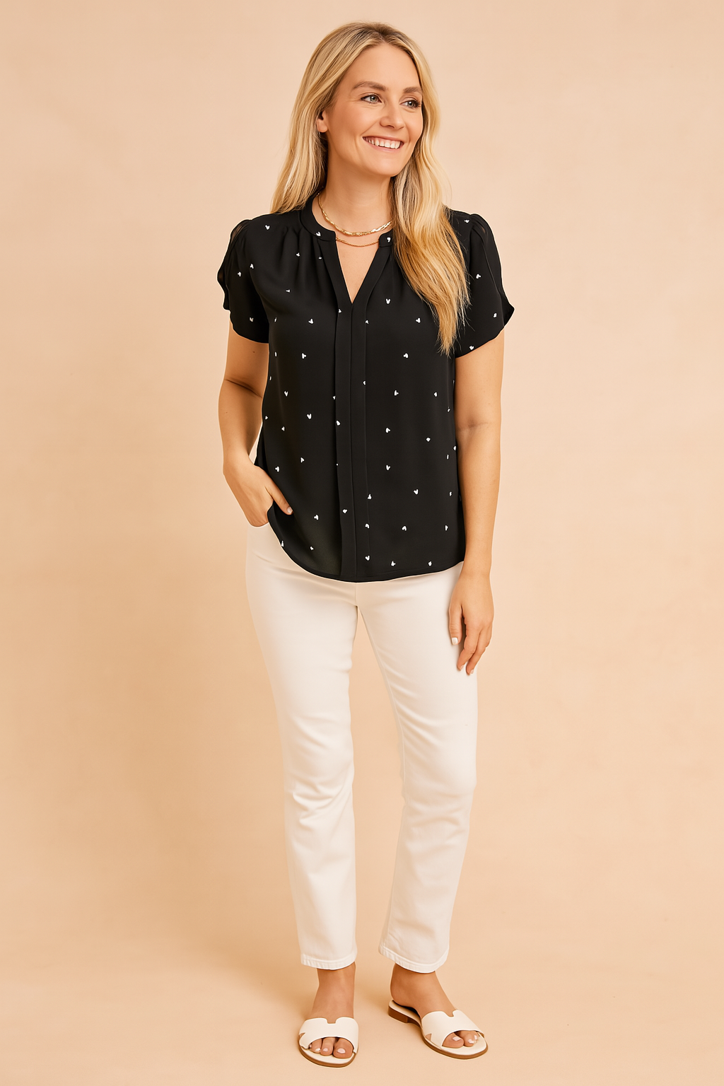 Zwarte blouse met korte mouwen en witte hartjesprint, met keyhole-halslijn en lichte, elegante afwerking.