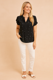 Zwarte blouse met korte mouwen en witte hartjesprint, met keyhole-halslijn en lichte, elegante afwerking.