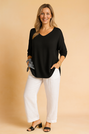 Tijdloze zwarte knit trui met comfortabele losse pasvorm, V-hals en 3/4-mouwen. Afgewerkt met geribde zoom en manchetten voor een elegante, moderne look.