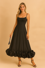 Zwarte midi-jurk met spaghetti bandjes, getailleerd silhouet en opvallende ballonzoom aan de onderkant.
