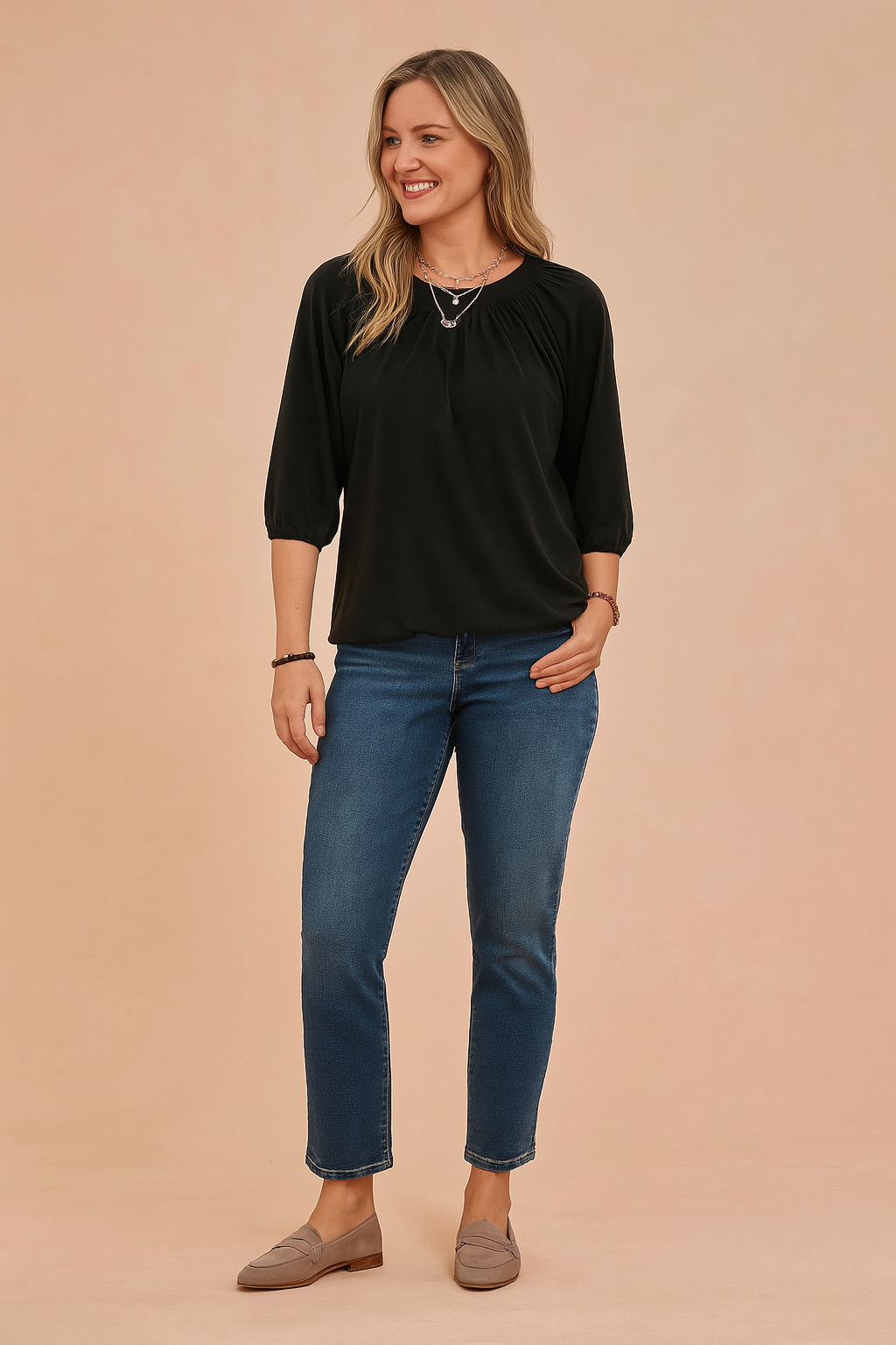 Zwarte dames top met ronde hals en driekwartmouwen, voorzien van elegante plooidetails rond de halslijn en licht gepofte mouwen met elastische boorden. Gemaakt van een soepele, effen jersey stof in een losvallende pasvorm die zowel comfort als een verfijnde uitstraling biedt.